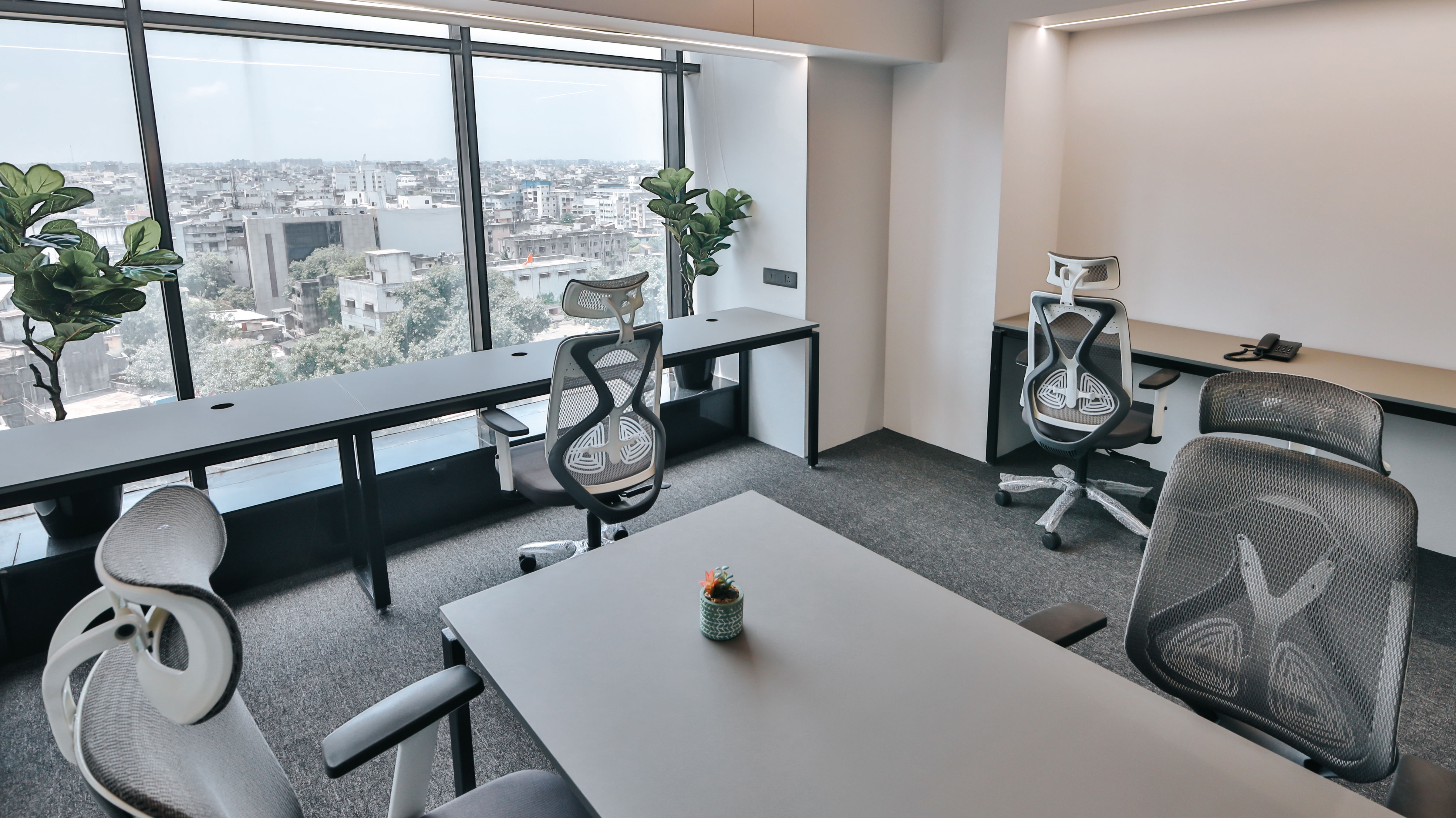 Modern hot desk office workspace with ergonomic chairs, shared desks, large windows, and city view, designed for flexible and collaborative work.