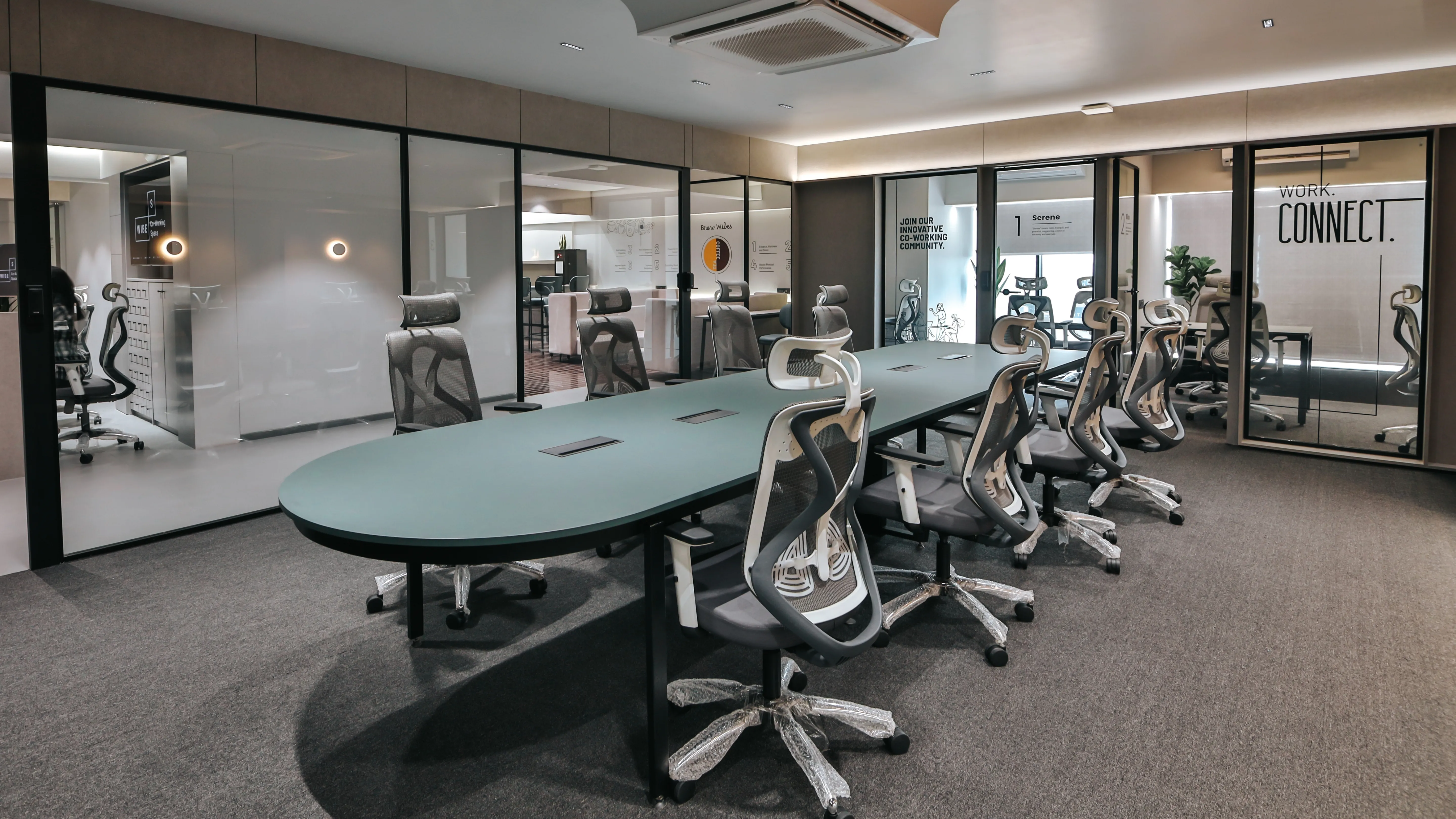 Modern coworking meeting room with a long conference table, ergonomic office chairs, and glass meeting rooms in a professional shared workspace