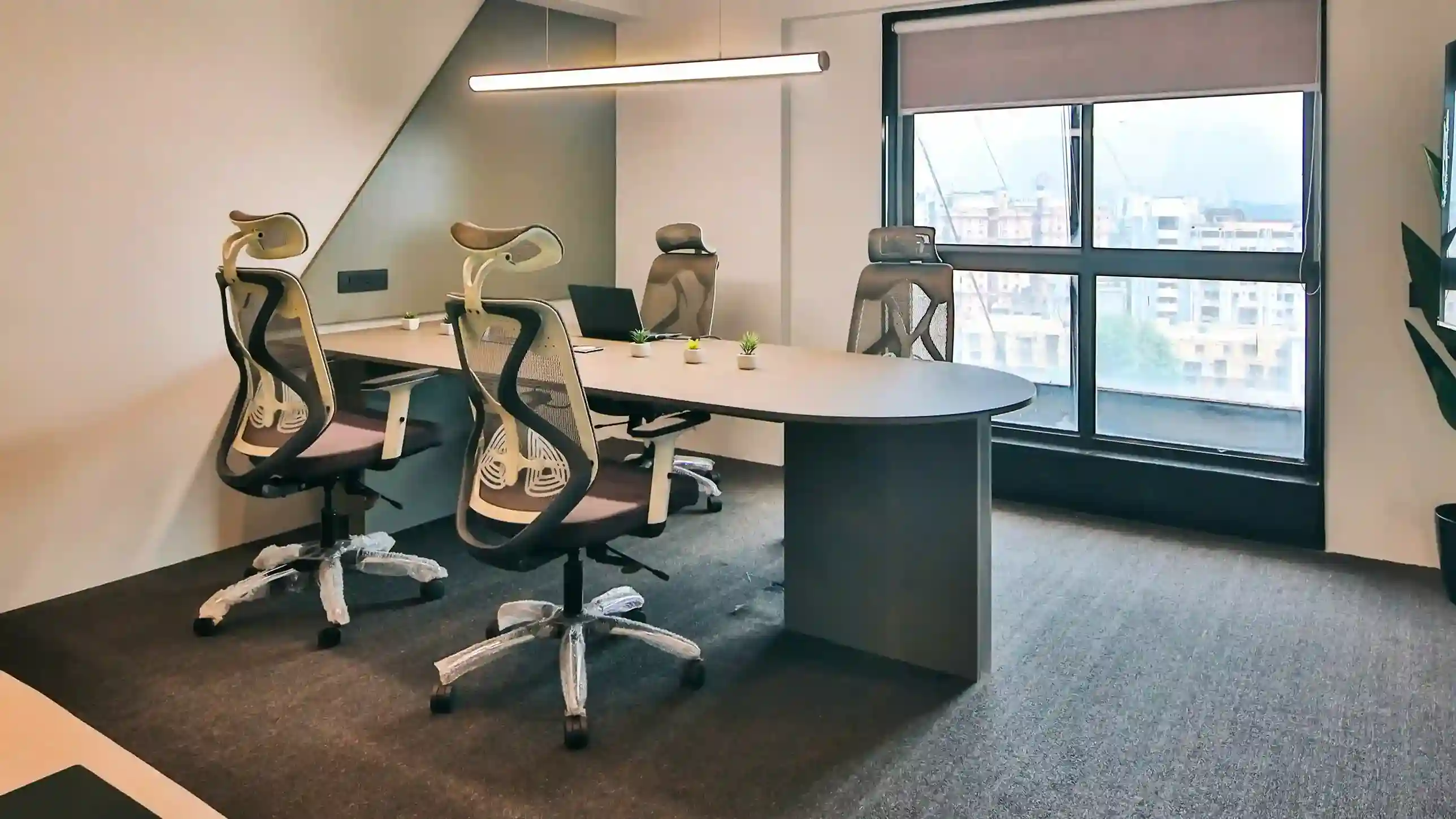 Modern meeting room with ergonomic chairs, large table, and natural light from windows, ideal for team discussions and client meetings