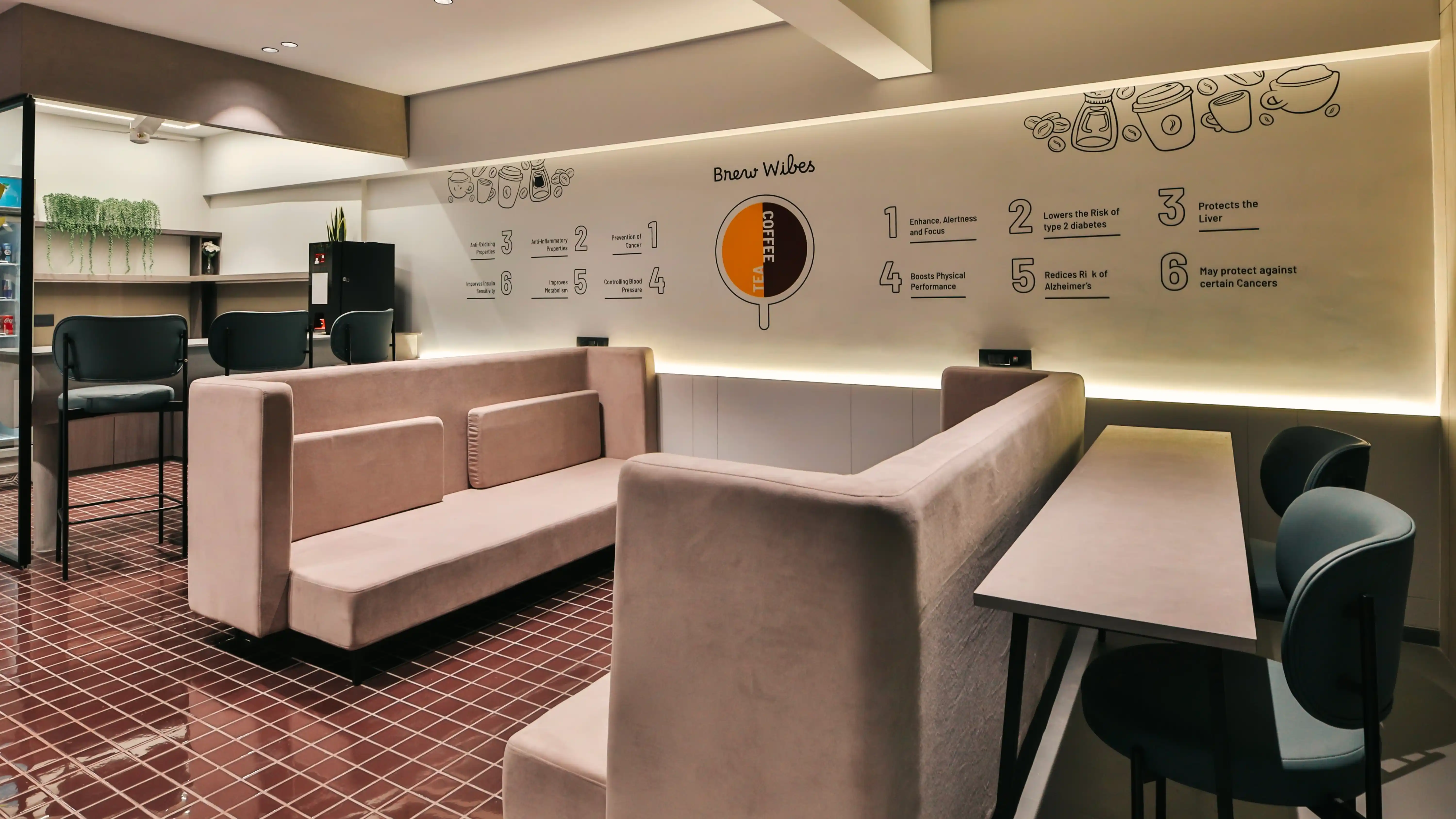 Cozy lounge area in Wibes coworking space with soft seating, high chairs, and wall graphics illustrating coffee benefits and wellness tips.