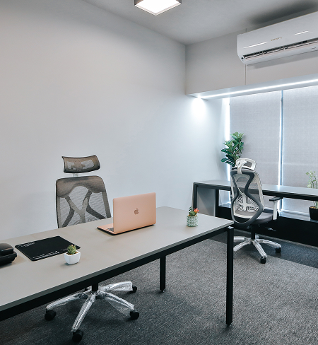Modern private office with ergonomic chairs, a spacious desk, an open laptop, indoor plants, and large windows in a bright, minimalist workspace.